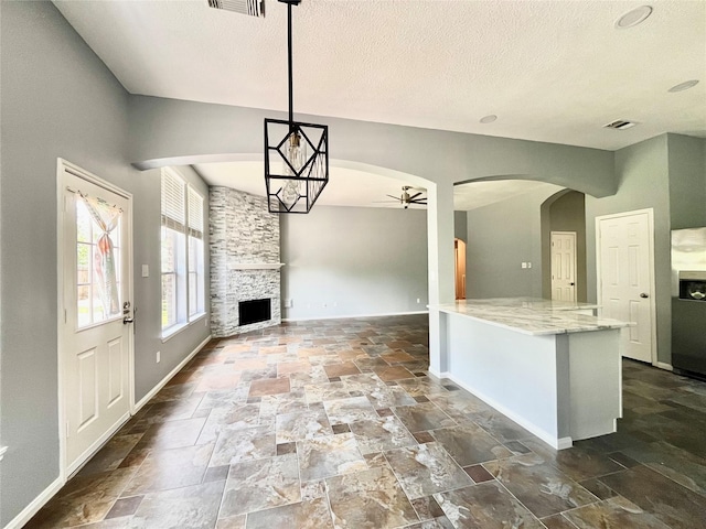 3209 Crimson Coast Dr, League City, TX 77573 - kitchen with stone tile floors, a ceiling fan, baseboards, arched walkways, and a textured ceiling