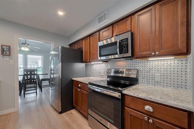64 Hideaway Dr, Friendswood, TX 77546 - kitchen featuring stainless steel appliances, light wood finished floors, tasteful backsplash, brown cabinets, and ceiling fan