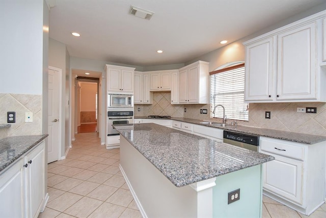 16535 Ruby Meadow Dr, Houston, TX 77095 - kitchen with stainless steel appliances, a sink, light tile patterned flooring, a kitchen island, and white cabinetry
