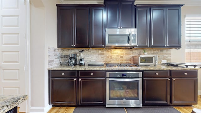 1911 Thunder Ridge Way, Houston, TX 77089 - kitchen featuring appliances with stainless steel finishes, tasteful backsplash, light wood finished floors, and light stone countertops