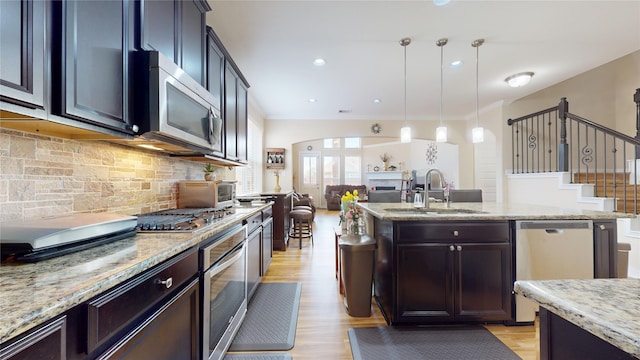 1911 Thunder Ridge Way, Houston, TX 77089 - kitchen featuring stainless steel appliances, a sink, a kitchen island with sink, light wood-style flooring, and decorative backsplash