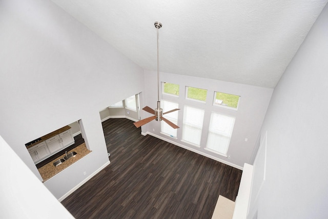 2385 Golden Shores Ln, League City, TX 77573 - unfurnished living room featuring dark wood-type flooring, baseboards, vaulted ceiling, a ceiling fan, and a sink