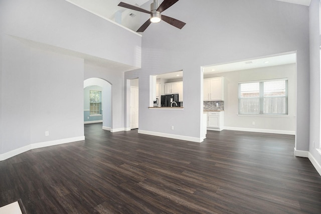 2385 Golden Shores Ln, League City, TX 77573 - unfurnished living room with a ceiling fan, arched walkways, high vaulted ceiling, dark wood finished floors, and baseboards