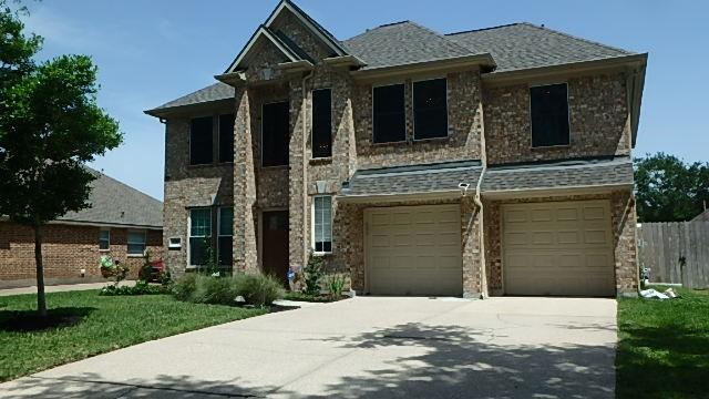2385 Golden Shores Ln, League City, TX 77573 - view of front facade featuring driveway, a garage, stone siding, and roof with shingles