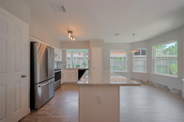8547 Sparkling Springs Dr, Houston, TX 77095 - kitchen featuring appliances with stainless steel finishes, plenty of natural light, a kitchen island, and white cabinetry