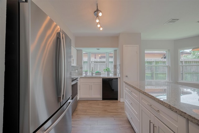 8547 Sparkling Springs Dr, Houston, TX 77095 - kitchen with stainless steel appliances, a sink, white cabinets, light stone countertops, and light wood finished floors