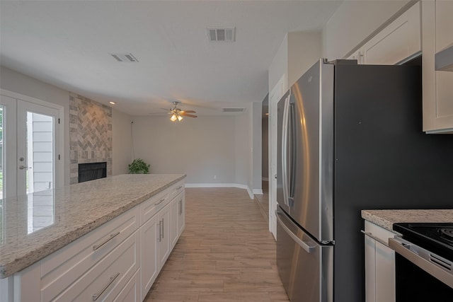 8547 Sparkling Springs Dr, Houston, TX 77095 - kitchen featuring white cabinets, light wood-style floors, a large fireplace, and ceiling fan