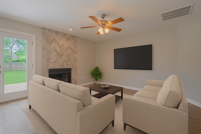 8547 Sparkling Springs Dr, Houston, TX 77095 - living area featuring a tiled fireplace, ceiling fan, baseboards, light wood finished floors, and recessed lighting