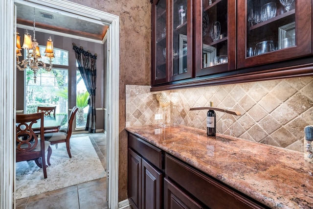 bar area featuring a chandelier, backsplash, and hanging light fixtures