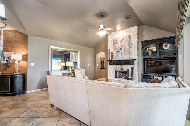 living area with vaulted ceiling, a ceiling fan, a fireplace, light tile patterned floors, and baseboards