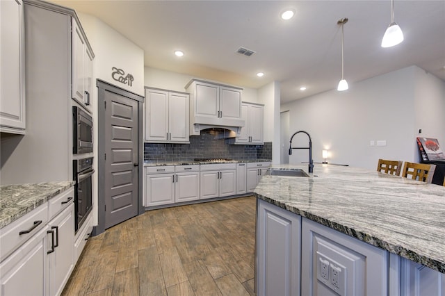 28723 Eden Creek Trl, Fulshear, TX 77441 - kitchen with a sink, stainless steel appliances, dark wood-style flooring, tasteful backsplash, and light stone countertops