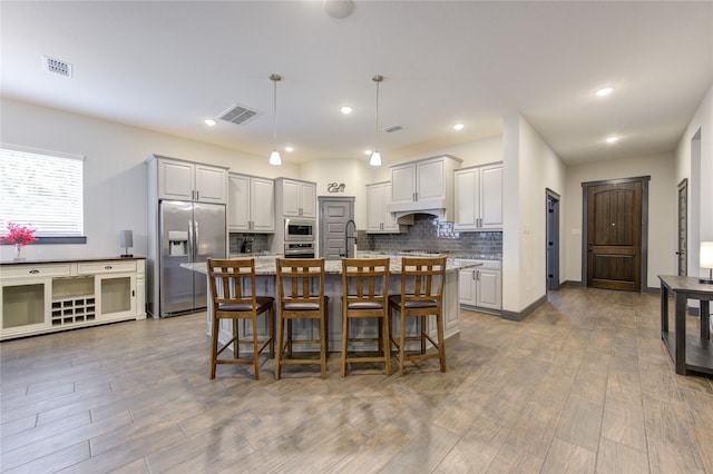 28723 Eden Creek Trl, Fulshear, TX 77441 - kitchen featuring stainless steel appliances, a center island with sink, backsplash, a breakfast bar, and wood finished floors