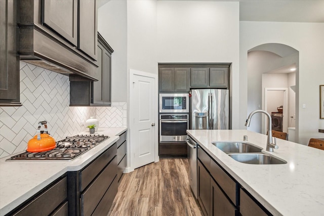 16707 Ramsay Cascades Dr, Humble, TX 77346 - kitchen with stainless steel appliances, a sink, arched walkways, wood finished floors, and light stone countertops