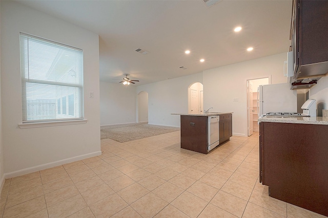 kitchen featuring arched walkways, dishwasher, light tile patterned floors, dark brown cabinets, and recessed lighting