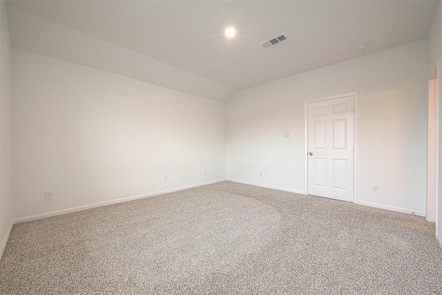 carpeted spare room with vaulted ceiling and baseboards