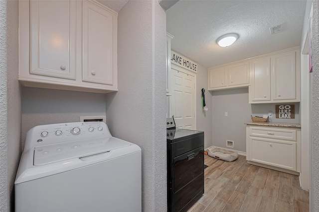 14844 Pollux Dr, Willis, TX 77318 - laundry room with washer / dryer, light wood-style flooring, a textured ceiling, baseboards, and cabinet space