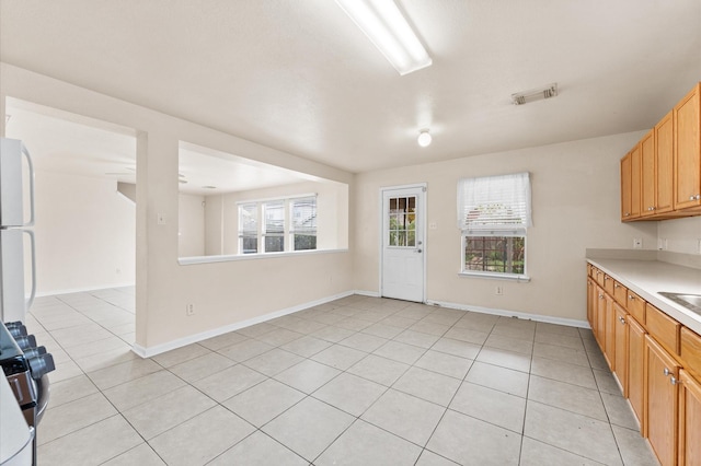 15427 Western Skies Dr, Houston, TX 77086 - kitchen with light countertops, light tile patterned floors, baseboards, stove, and freestanding refrigerator