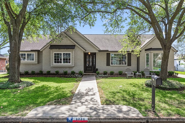 single story home featuring a front lawn, brick siding, and roof with shingles