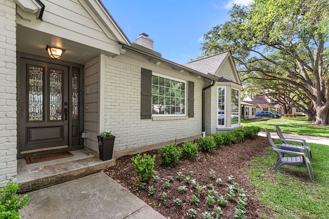 doorway to property featuring brick siding and a chimney