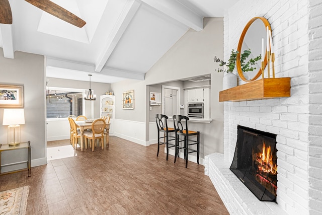 living room with wood finished floors, a fireplace, and a wainscoted wall