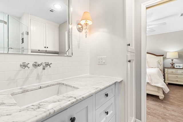 full bath with decorative backsplash, connected bathroom, ceiling fan, vanity, and tiled shower