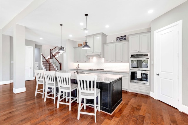 30622 Indigo Falls Dr, Brookshire, TX 77423 - kitchen with appliances with stainless steel finishes, decorative backsplash, a kitchen island with sink, a sink, and a breakfast bar area