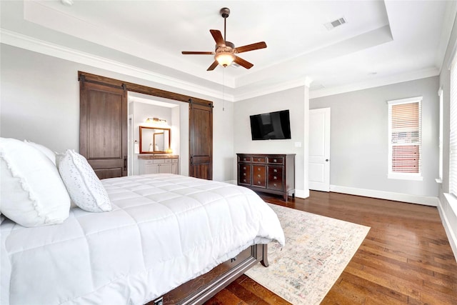 30622 Indigo Falls Dr, Brookshire, TX 77423 - bedroom with a tray ceiling, a barn door, dark wood-style floors, baseboards, and ornamental molding