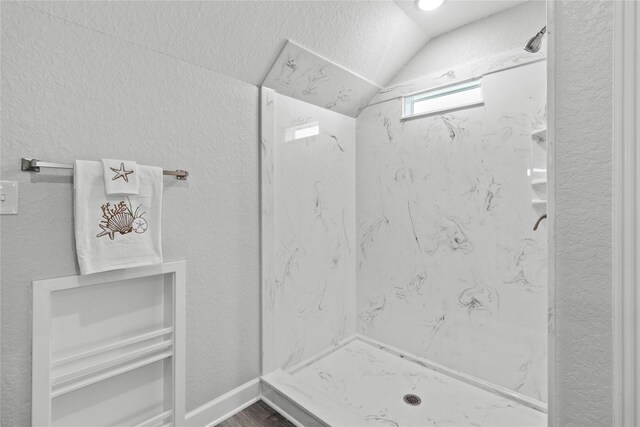 206 San Luis Blvd, Freeport, TX 77541 - bathroom featuring lofted ceiling, a marble finish shower, a textured wall, and wood finished floors