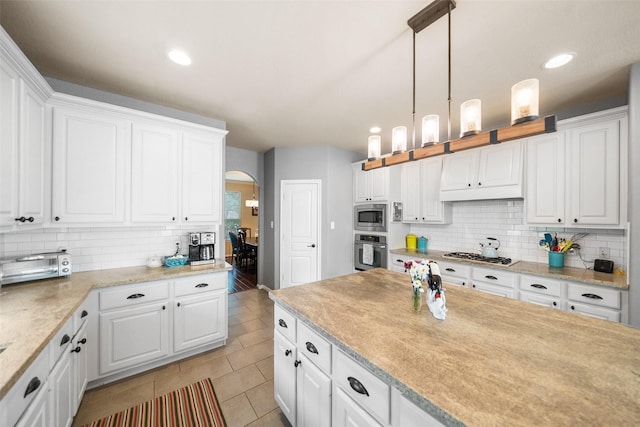 2510 Eagle Post Dr, Conroe, TX 77304 - kitchen with appliances with stainless steel finishes, arched walkways, tasteful backsplash, white cabinets, and light countertops