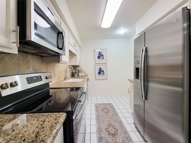 1201 Bering Dr Unit 44, Houston, TX 77057 - kitchen with stainless steel appliances, a sink, backsplash, light tile patterned floors, and white cabinets