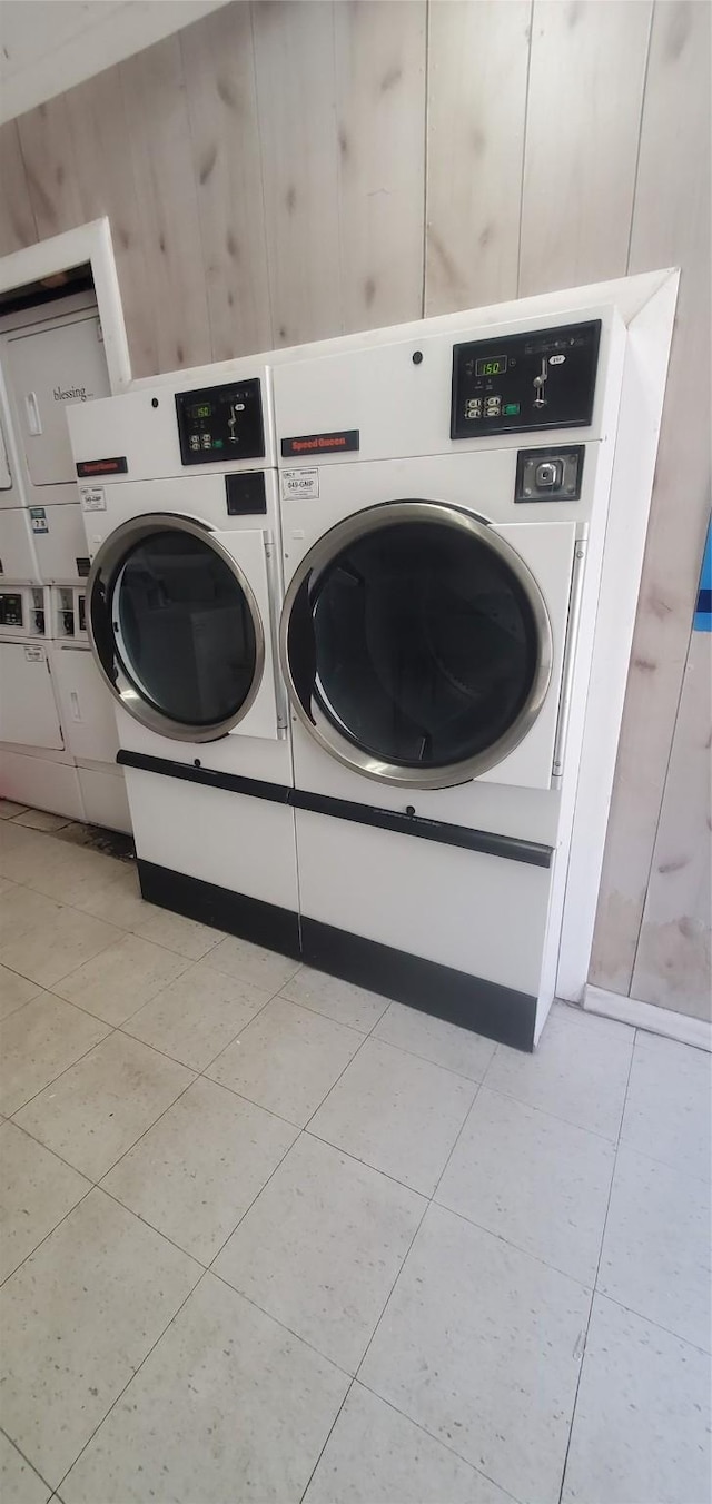 8941 Gaylord St Unit 211, Houston, TX 77024 - shared laundry featuring washer and clothes dryer, stacked washer / drying machine, light tile patterned floors, and wood walls