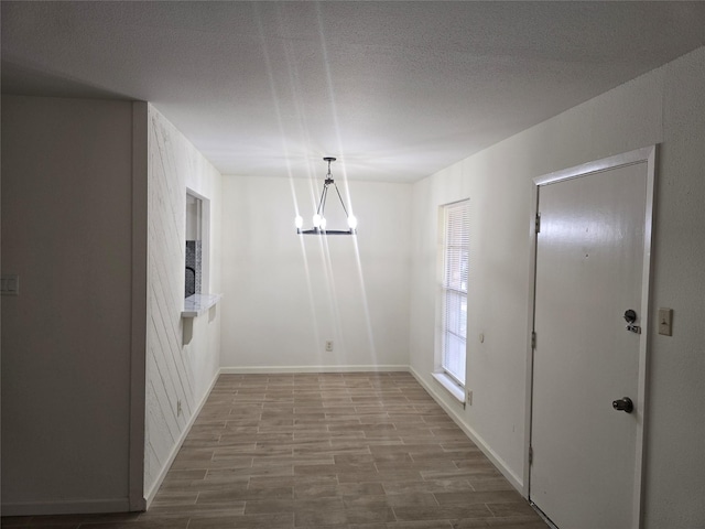 8941 Gaylord St Unit 211, Houston, TX 77024 - unfurnished dining area with a chandelier, a textured ceiling, and wood finished floors