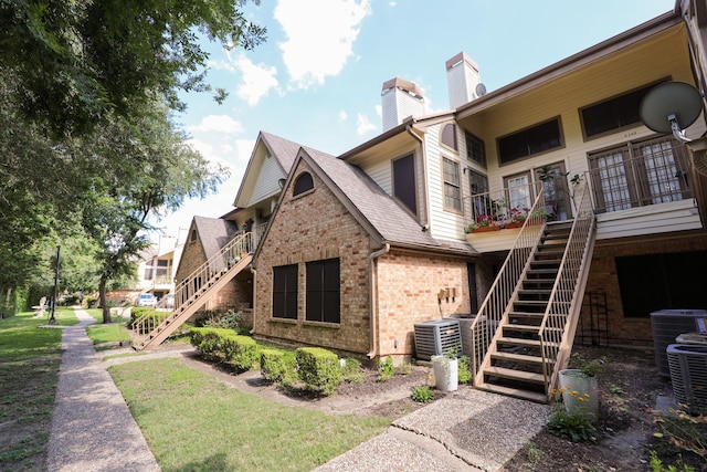 2425 Holly Hall St Unit 149, Houston, TX 77054 - view of home's exterior with stairs, a chimney, brick siding, and cooling unit