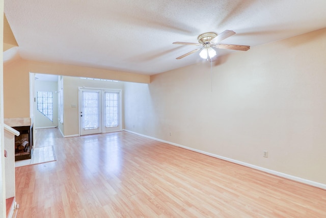2425 Holly Hall St Unit 149, Houston, TX 77054 - unfurnished living room with light wood-type flooring, a tile fireplace, a ceiling fan, baseboards, and a textured ceiling