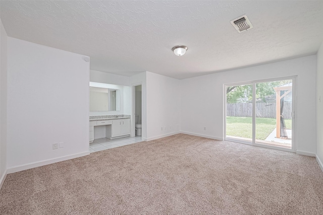 7011 Maple Fox Dr, Humble, TX 77338 - unfurnished living room featuring light carpet, baseboards, and a textured ceiling