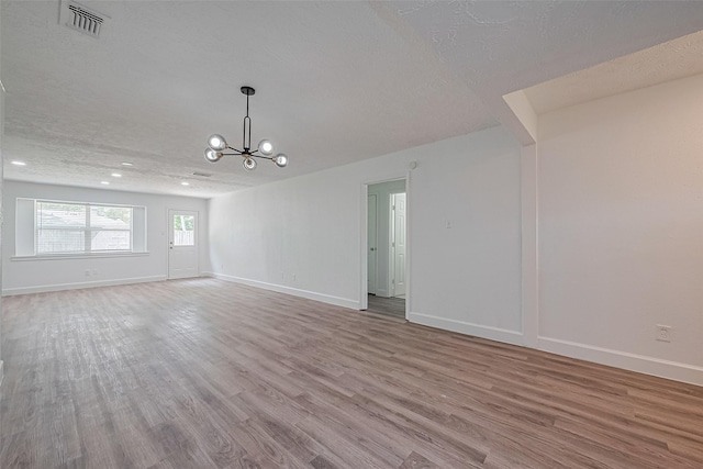 7011 Maple Fox Dr, Humble, TX 77338 - unfurnished living room with wood finished floors, a chandelier, baseboards, a textured ceiling, and recessed lighting