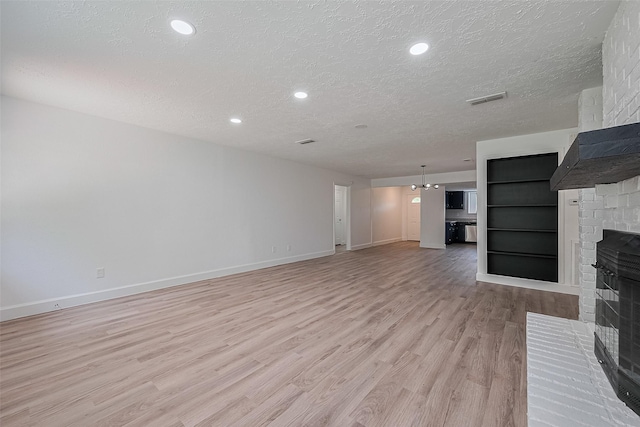 7011 Maple Fox Dr, Humble, TX 77338 - unfurnished living room featuring a brick fireplace, a textured ceiling, light wood-style floors, baseboards, and recessed lighting