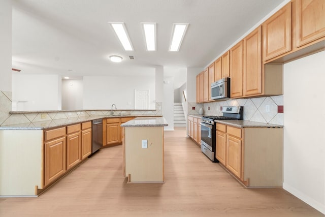 19827 Lajuana Ln, Spring, TX 77388 - kitchen with appliances with stainless steel finishes, light wood finished floors, a peninsula, a sink, and decorative backsplash