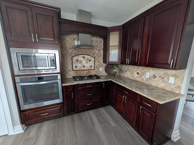 10067 Lazy Meadows Dr, Houston, TX 77064 - kitchen with stainless steel appliances, wall chimney range hood, light wood-type flooring, and a textured ceiling