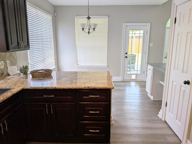 10067 Lazy Meadows Dr, Houston, TX 77064 - kitchen with a peninsula, wood finished floors, backsplash, pendant lighting, and light stone counters
