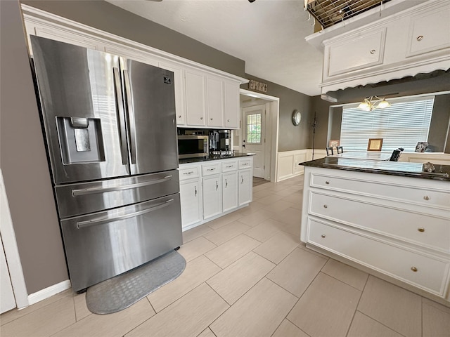 17407 Majestic Forest Dr, Spring, TX 77379 - kitchen with appliances with stainless steel finishes, dark countertops, white cabinets, wainscoting, and light tile patterned flooring