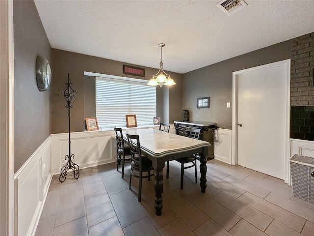 17407 Majestic Forest Dr, Spring, TX 77379 - tiled dining space with a textured ceiling, a decorative wall, and a wainscoted wall