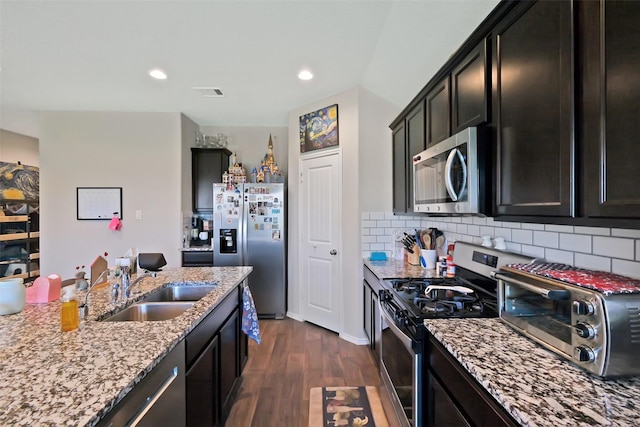 8434 Violet Hills Ln, Rosharon, TX 77583 - kitchen featuring stainless steel appliances, dark wood-style floors, light stone counters, a sink, and decorative backsplash