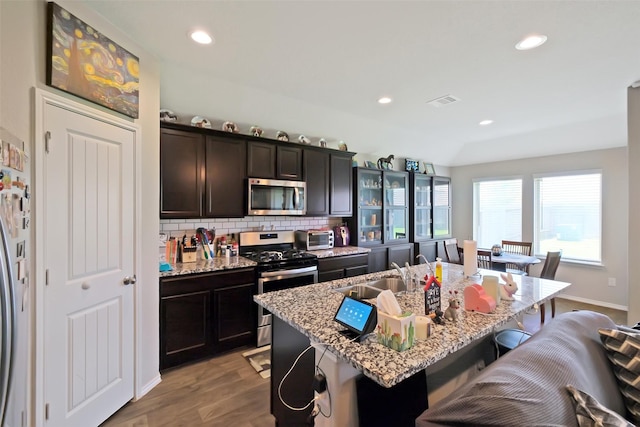 8434 Violet Hills Ln, Rosharon, TX 77583 - kitchen featuring appliances with stainless steel finishes, a sink, a kitchen breakfast bar, backsplash, and light wood finished floors