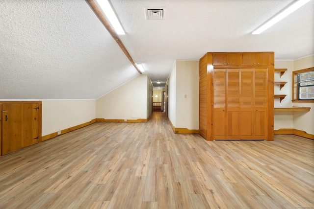 1000 W Polk St, Livingston, TX 77351 - additional living space featuring a textured ceiling, light wood finished floors, baseboards, and vaulted ceiling