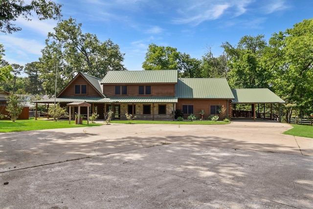1000 W Polk St, Livingston, TX 77351 - view of front of property featuring covered porch, concrete driveway, a carport, metal roof, and stone siding