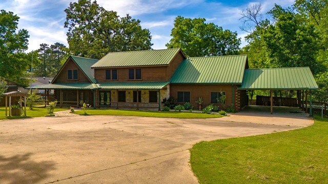 1000 W Polk St, Livingston, TX 77351 - view of front of home with a front yard, driveway, metal roof, a carport, and log exterior