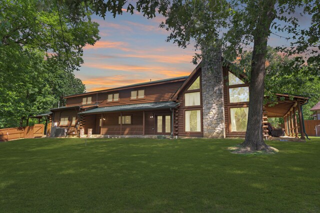 1000 W Polk St, Livingston, TX 77351 - back of house at dusk featuring log exterior, central AC, and metal roof