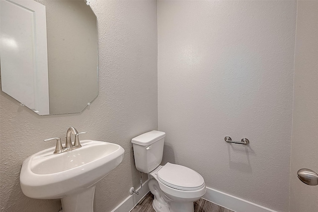 7703 Rainbow Close Ln, Houston, TX 77055 - half bath featuring a sink, toilet, wood finished floors, and baseboards