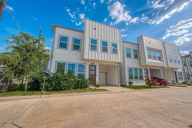 7703 Rainbow Close Ln, Houston, TX 77055 - townhome / multi-family property featuring a garage, concrete driveway, fence, and board and batten siding